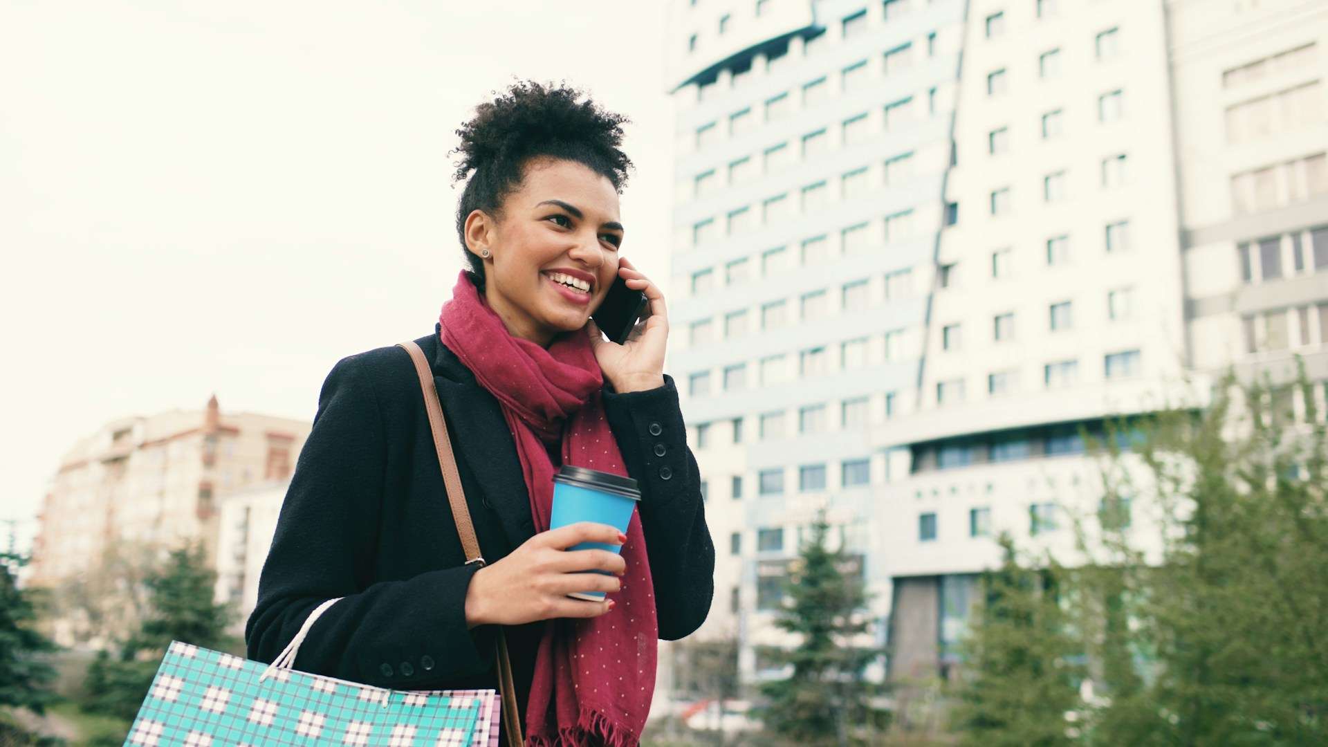 Woman on the phone walking and holding coffee